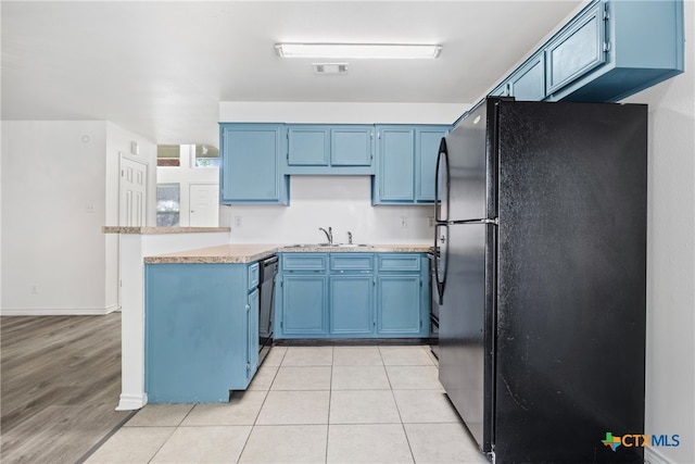 kitchen with sink, black appliances, kitchen peninsula, blue cabinets, and light wood-type flooring