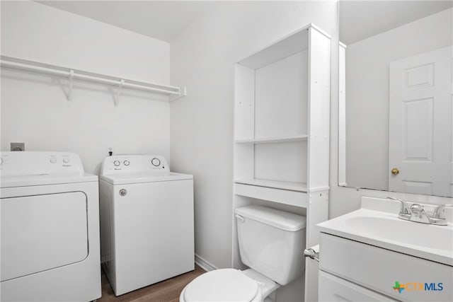 bathroom featuring wood-type flooring, toilet, vanity, and washer and dryer