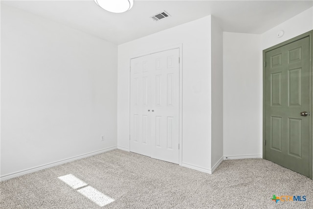 unfurnished bedroom featuring a closet and light carpet