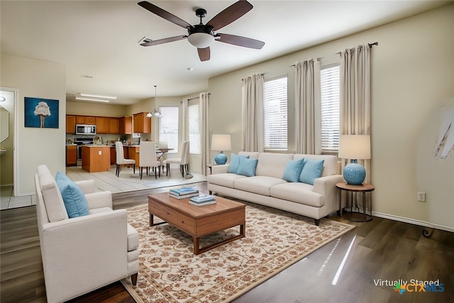 living room with light hardwood / wood-style floors, ceiling fan with notable chandelier, and plenty of natural light