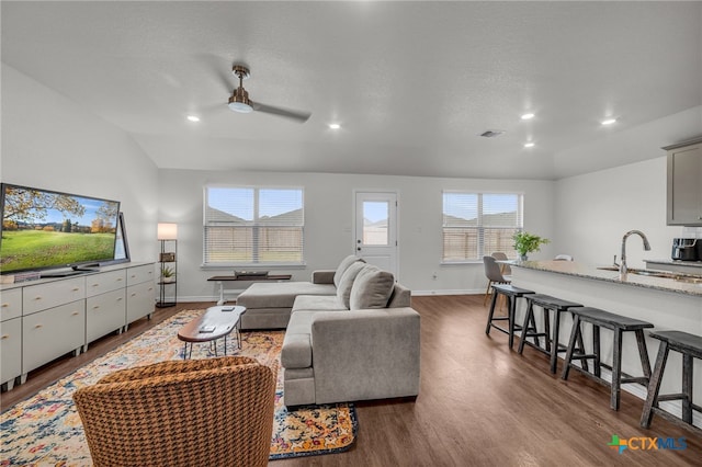 living room featuring hardwood / wood-style flooring, lofted ceiling, sink, and ceiling fan