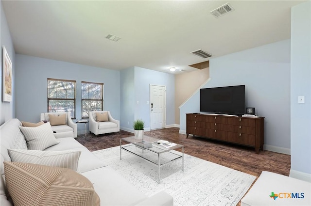 living room with baseboards, visible vents, and wood finished floors