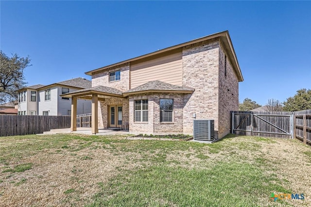rear view of property with a fenced backyard, a lawn, central AC, and a patio area