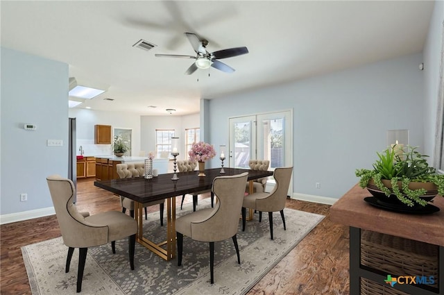 dining area featuring visible vents, a ceiling fan, baseboards, and wood finished floors