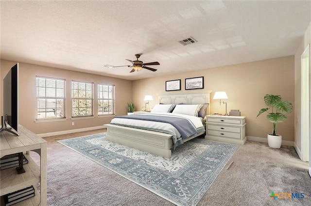 bedroom with light colored carpet, baseboards, visible vents, and ceiling fan