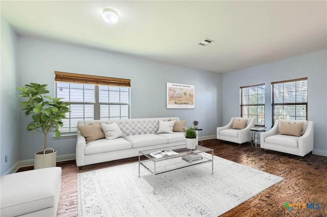 living room featuring baseboards, visible vents, and wood finished floors