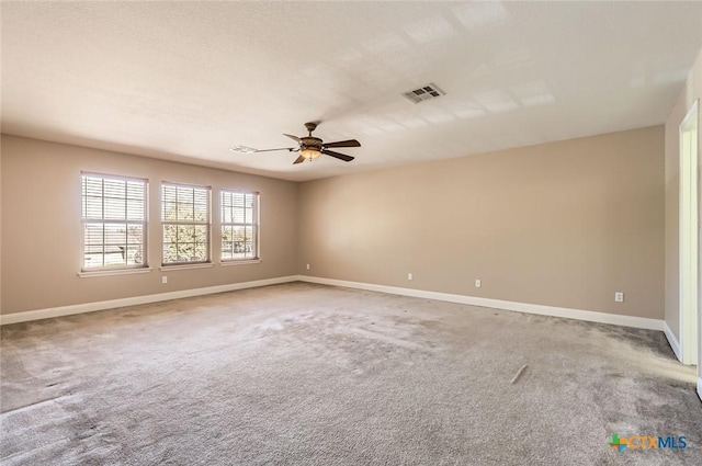 unfurnished room with light colored carpet, baseboards, visible vents, and ceiling fan