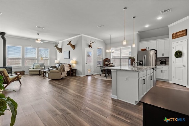 kitchen featuring visible vents, open floor plan, stainless steel fridge, white cabinets, and crown molding