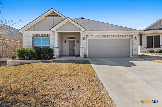 view of front of property featuring driveway, a garage, board and batten siding, and stone siding