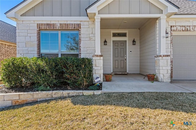 doorway to property with stone siding, board and batten siding, an attached garage, and a shingled roof