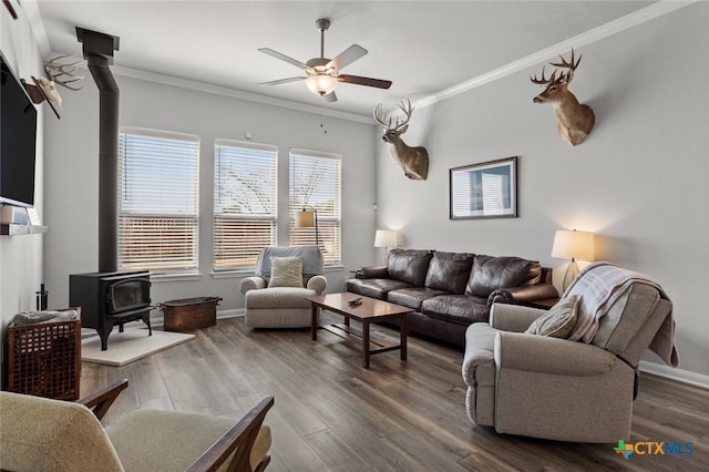 living room featuring crown molding, a wood stove, ceiling fan, and dark wood-style flooring