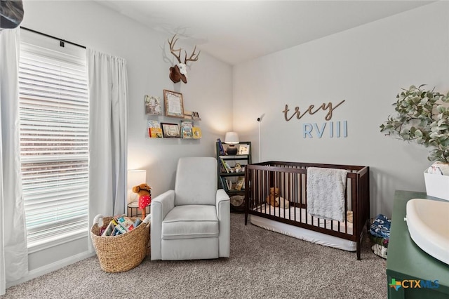 bedroom with a sink, multiple windows, a crib, and carpet flooring