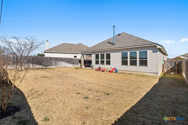 back of house featuring a yard, a fenced backyard, and a shingled roof