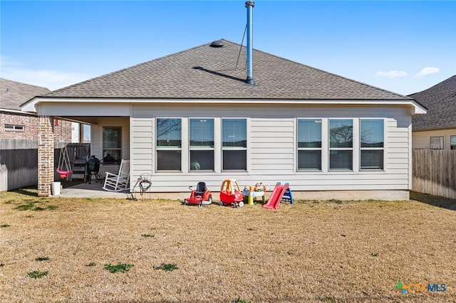 rear view of house featuring a yard, a patio area, a fenced backyard, and roof with shingles