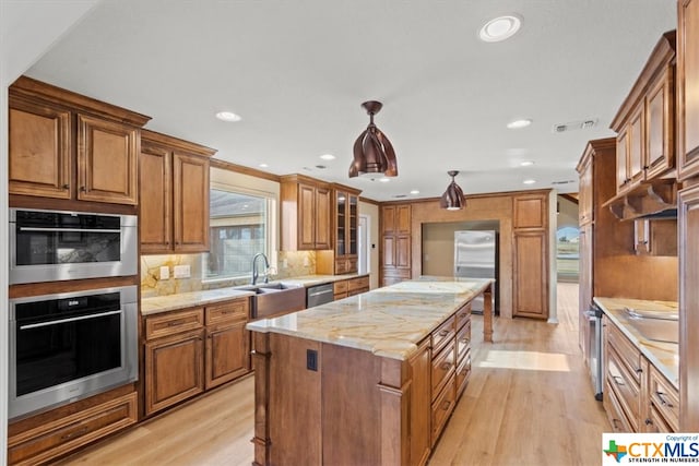 kitchen with light hardwood / wood-style flooring, hanging light fixtures, sink, and a center island