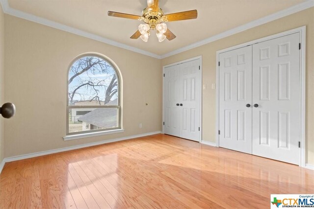 6503 Wells Fargo Rd, Killeen, TX 76542 - unfurnished bedroom featuring wood finished floors, baseboards, crown molding, two closets, and ceiling fan