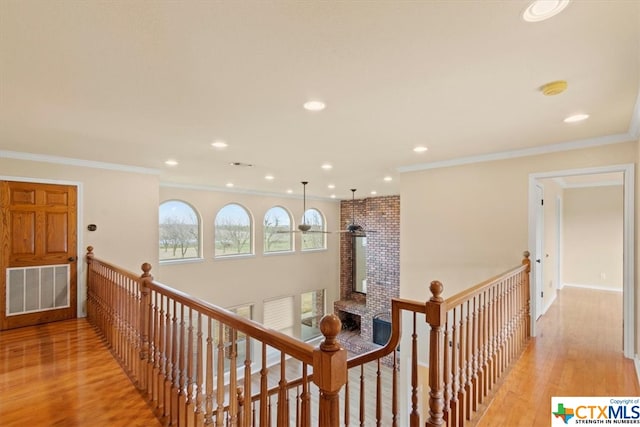 hallway with light wood-type flooring and crown molding