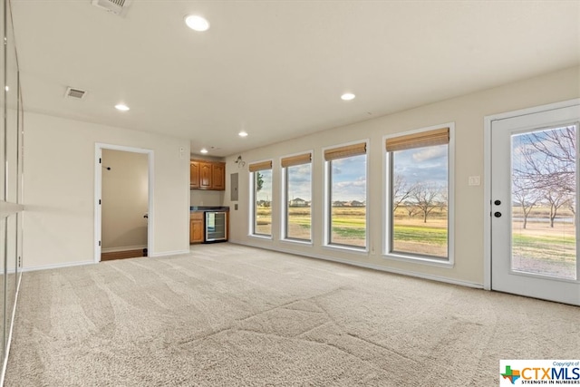 unfurnished living room featuring light colored carpet and wine cooler