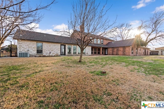 rear view of property featuring a lawn and central air condition unit