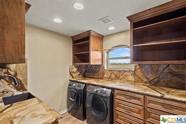 clothes washing area featuring light wood-type flooring, cabinets, and washing machine and clothes dryer