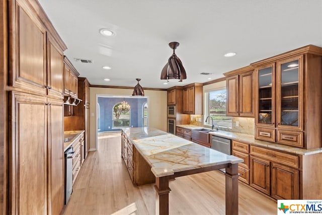 kitchen featuring sink, crown molding, pendant lighting, light wood-type flooring, and appliances with stainless steel finishes