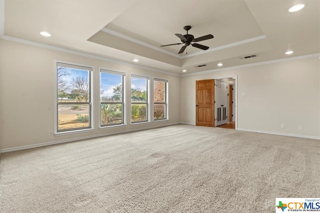 carpeted empty room featuring ceiling fan, a raised ceiling, and ornamental molding