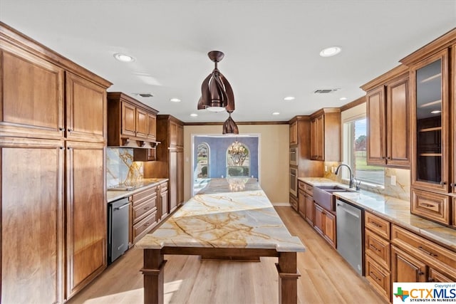 kitchen featuring stainless steel appliances, sink, backsplash, light hardwood / wood-style flooring, and decorative light fixtures