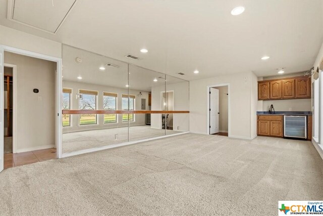 6503 Wells Fargo Rd, Killeen, TX 76542 - unfurnished living room featuring wine cooler, bar with sink, recessed lighting, light carpet, and baseboards