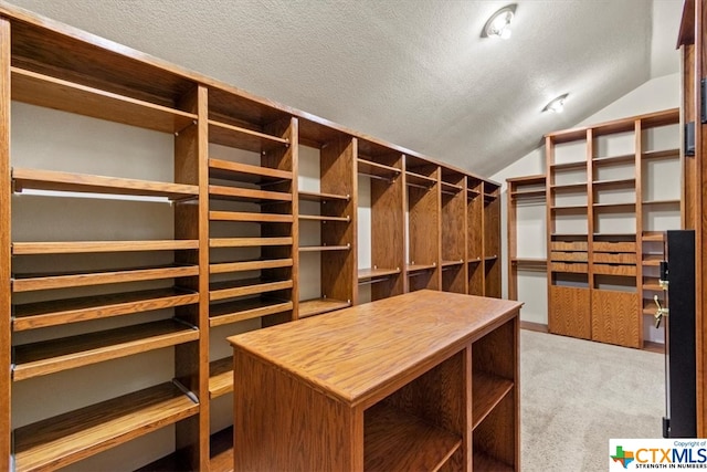 spacious closet featuring light colored carpet and lofted ceiling