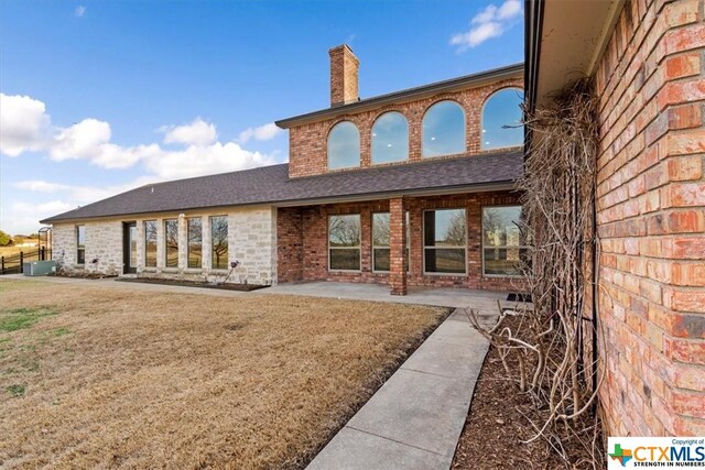 6503 Wells Fargo Rd, Killeen, TX 76542 - rear view of house with brick siding, a patio, a chimney, roof with shingles, and a lawn