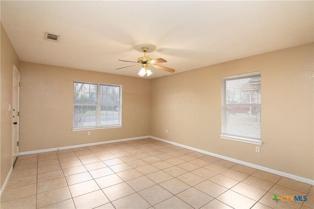 tiled empty room with a wealth of natural light and ceiling fan