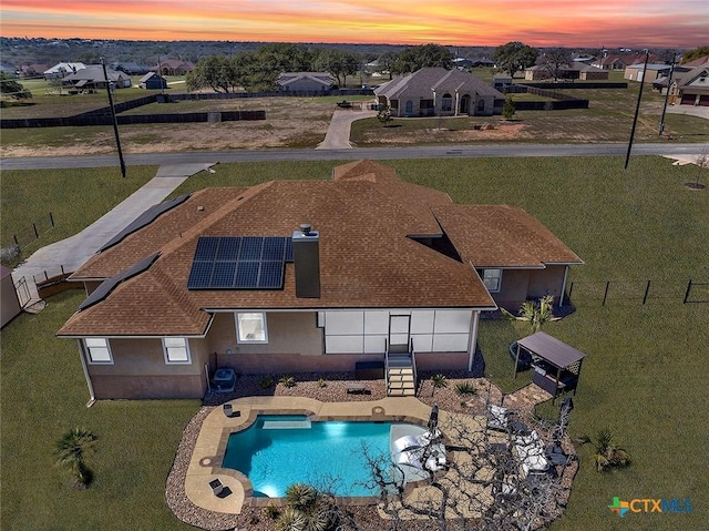 pool at dusk featuring a patio, fence, an outdoor pool, and a residential view