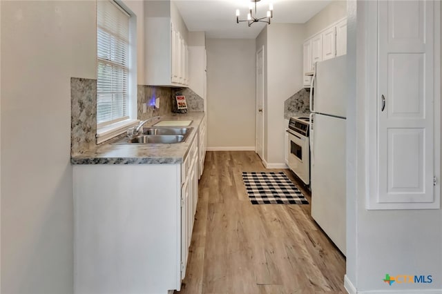 kitchen with white cabinetry, sink, a notable chandelier, light hardwood / wood-style floors, and white appliances