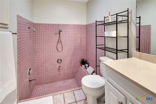 bathroom featuring tile patterned flooring, vanity, toilet, and tiled shower