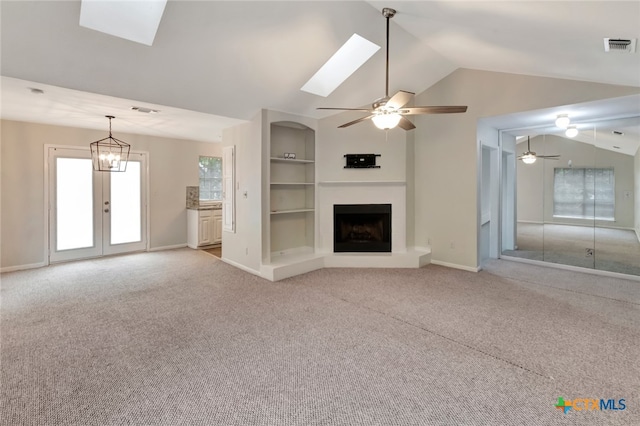 unfurnished living room with built in shelves, a healthy amount of sunlight, light colored carpet, and vaulted ceiling