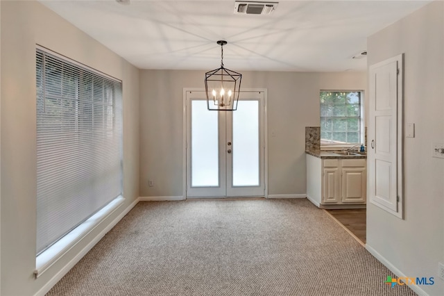 doorway to outside featuring french doors, carpet floors, an inviting chandelier, and sink