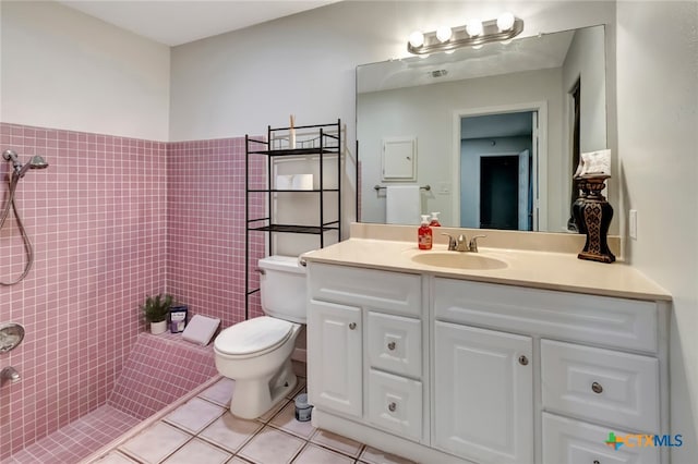 bathroom featuring vanity, tile patterned floors, toilet, tile walls, and a tile shower