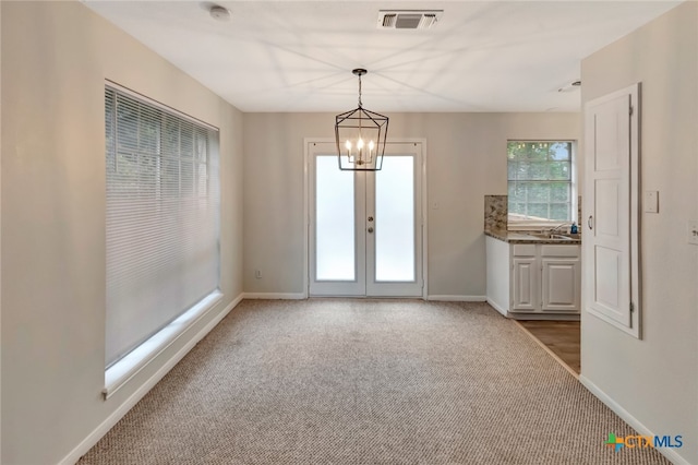 unfurnished dining area with carpet, french doors, and a chandelier