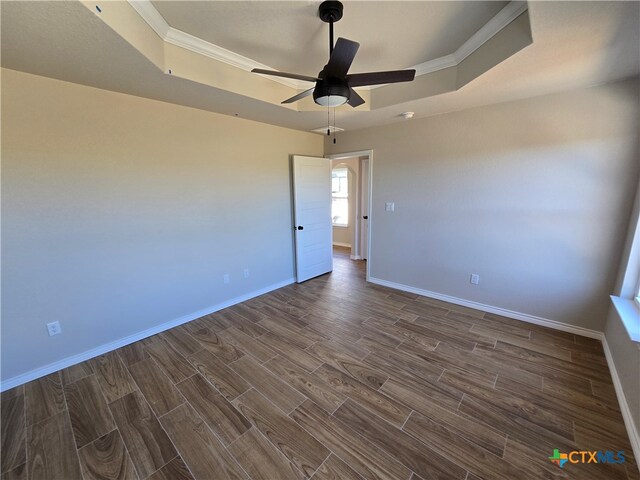 unfurnished room with ornamental molding, dark hardwood / wood-style floors, a raised ceiling, and ceiling fan