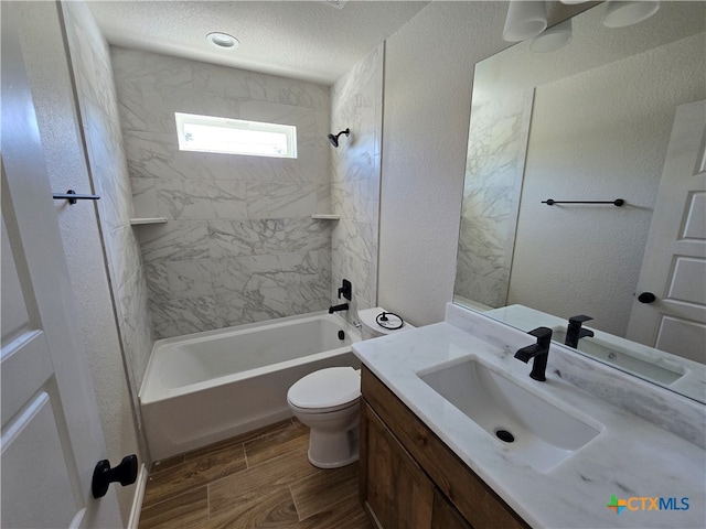 full bathroom featuring a textured ceiling, hardwood / wood-style floors, vanity, toilet, and tiled shower / bath combo