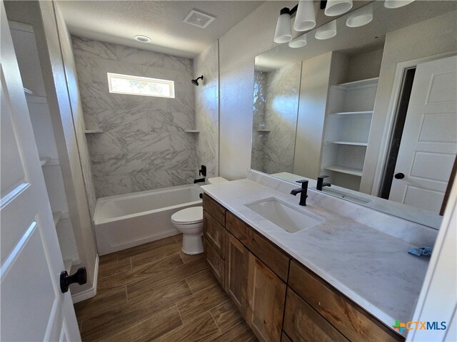 full bathroom featuring vanity, tiled shower / bath, toilet, and a textured ceiling