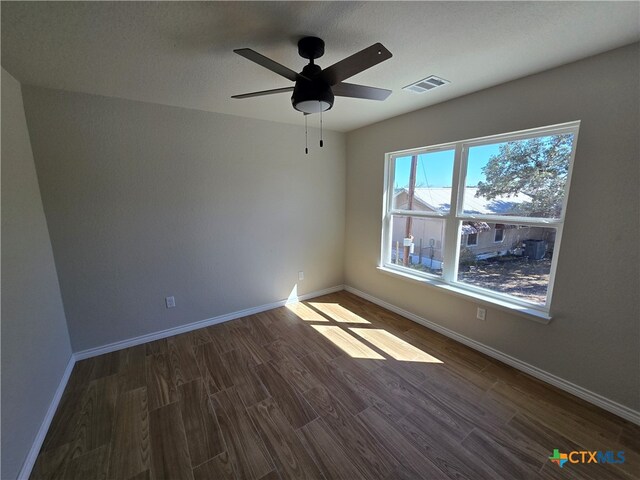 spare room with a textured ceiling, dark wood-type flooring, and ceiling fan