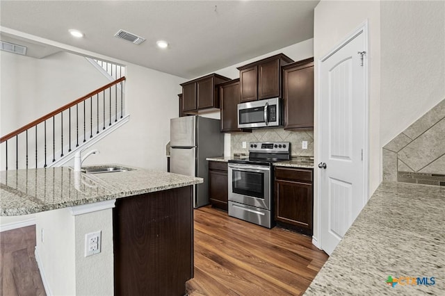 5101 Hacienda Dr, Killeen, TX 76549 - kitchen with stainless steel appliances, a sink, dark wood-style floors, decorative backsplash, and dark brown cabinets