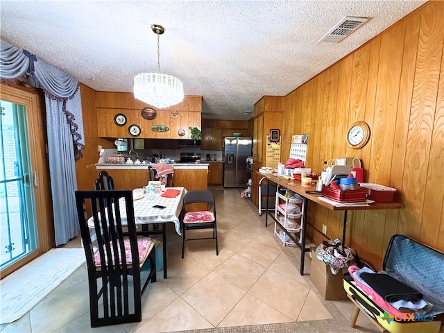 1901 Muir Dr, Killeen, TX 76543 - dining space featuring a chandelier, wood walls, a textured ceiling, and light tile patterned flooring