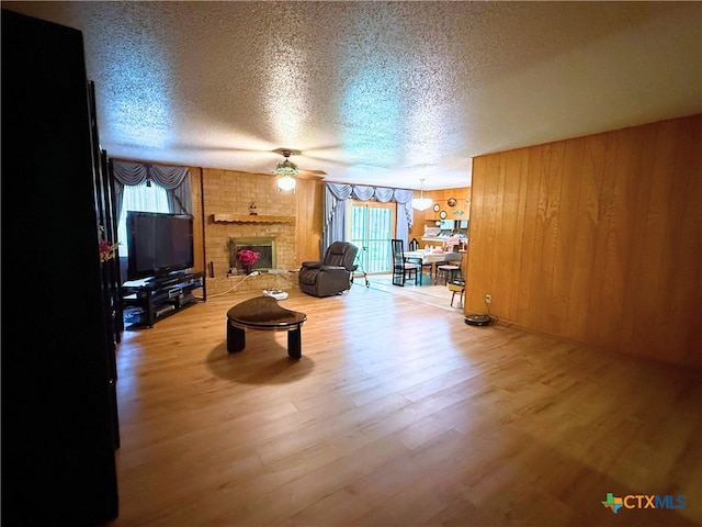1901 Muir Dr, Killeen, TX 76543 - living room featuring a ceiling fan, a textured ceiling, healthy amount of natural light, wood finished floors, and a fireplace