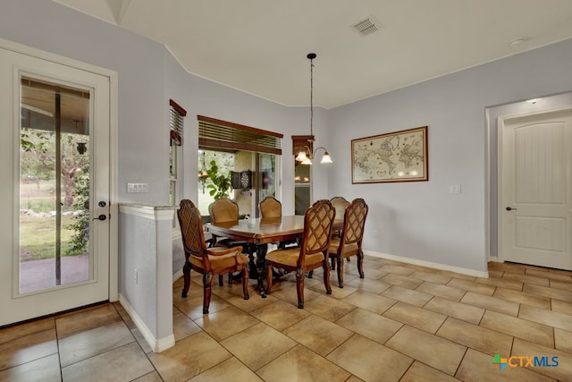 tiled dining room with an inviting chandelier and plenty of natural light