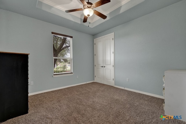 unfurnished room featuring carpet flooring, ceiling fan, a raised ceiling, and crown molding