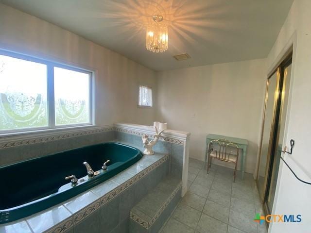 bathroom with an inviting chandelier, a garden tub, and tile patterned floors