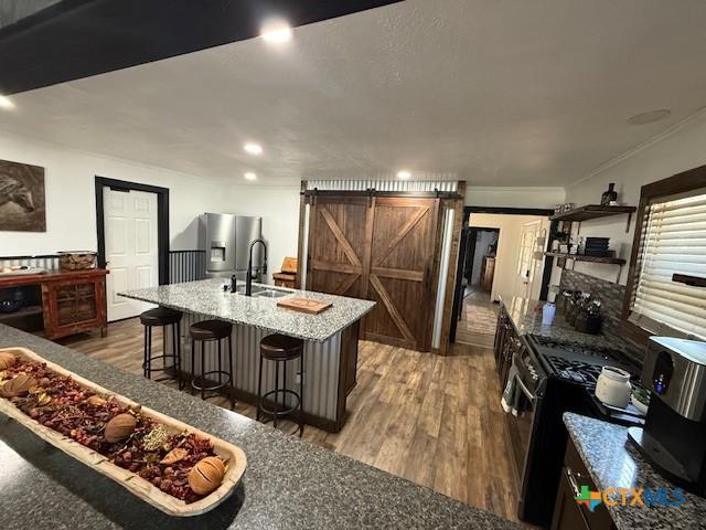 202 Clark St, Yoakum, TX 77995 - kitchen with a barn door, stainless steel appliances, a kitchen bar, wood finished floors, and recessed lighting
