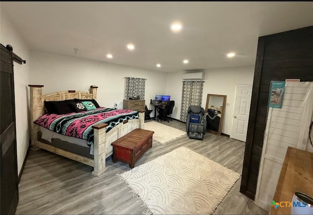 202 Clark St, Yoakum, TX 77995 - bedroom featuring a wall mounted air conditioner, a barn door, wood finished floors, and recessed lighting